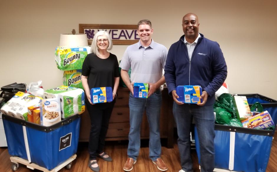 3 people with 2 bins on new items for donation, paper towels,  tupperware, dish towels, cereal.
